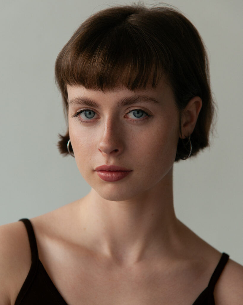 Model Elise Poliquin of Details the agency shot by Mégane Brunette, make up by Nelly C. The model is looking straight at the camera, there is soft window light hitting the side of her face.