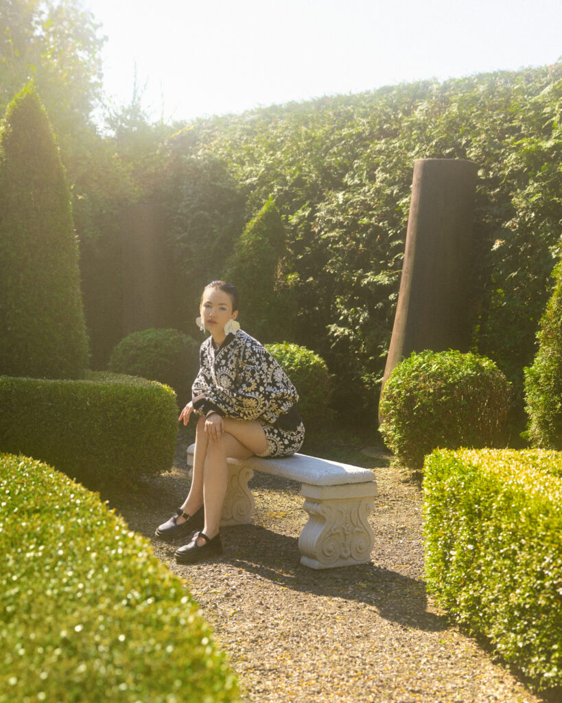 model Eva Lou of System Agency Montreal in a manicured garden, styled by Uyen Dao, hair and makeup by Gabbie Mcguire and photographed by Megane Brunette