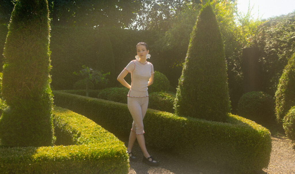 model Eva Lou of System Agency Montreal in a manicured garden, styled by Uyen Dao, hair and makeup by Gabbie Mcguire and photographed by Megane Brunette