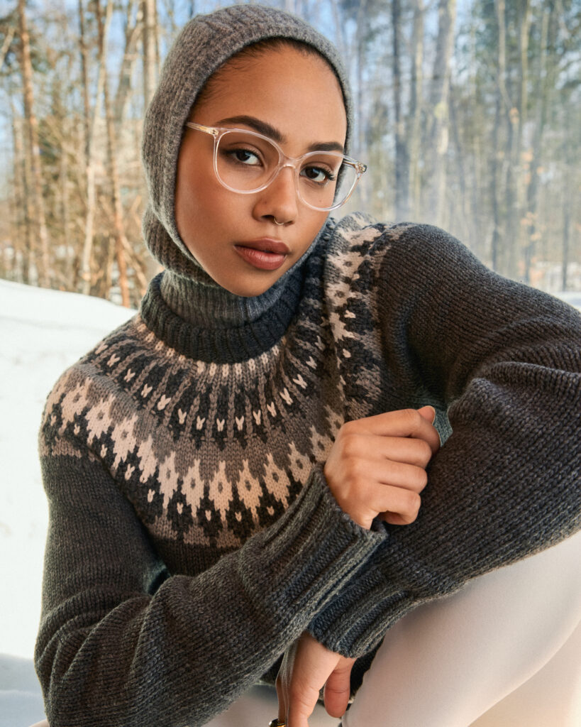 In a Holiday photoshoot for eyewear company Bonlook, model Trinity Faith of Folio Management wearing a fair isle sweater and a knit balaclava, sitting by a window revealing a beautiful winter landscape. Styled by Gabriel Dupuis, hair and makeup by Genevieve Lenneville of Folio Management, photographed by Megane Brunette.